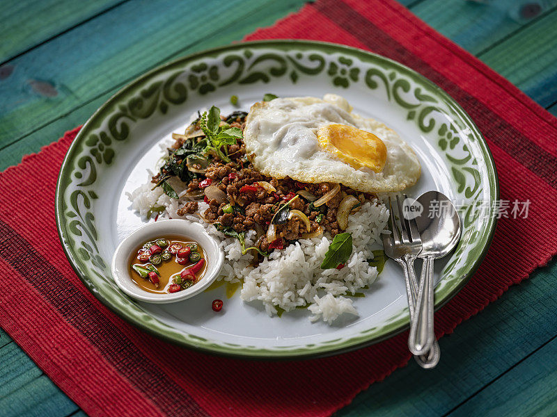 著名的泰国辣菜“Pak Krapao Moo”在英语中是用神圣罗勒炸猪肉，在一个古老的绿松石色风化木桌上用蒸饭和煎蛋和“Pik Nam Bla”(鱼酱辣椒)。